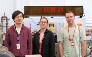 Three people stood in front of a "beam on" sign