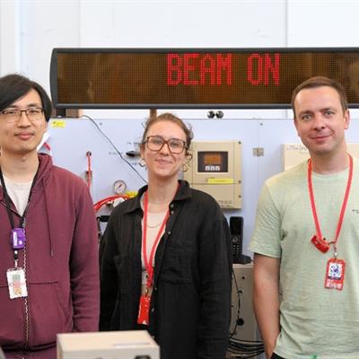 Three people stood in front of a "beam on" sign