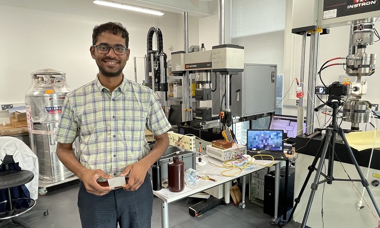 Ashwath Pazhani holding a piece of composite material in the lab