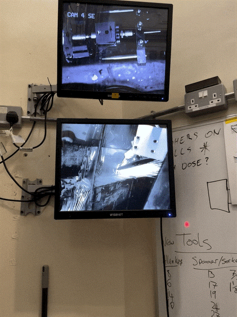 Two computer monitors, showing black and white images of sparks flying