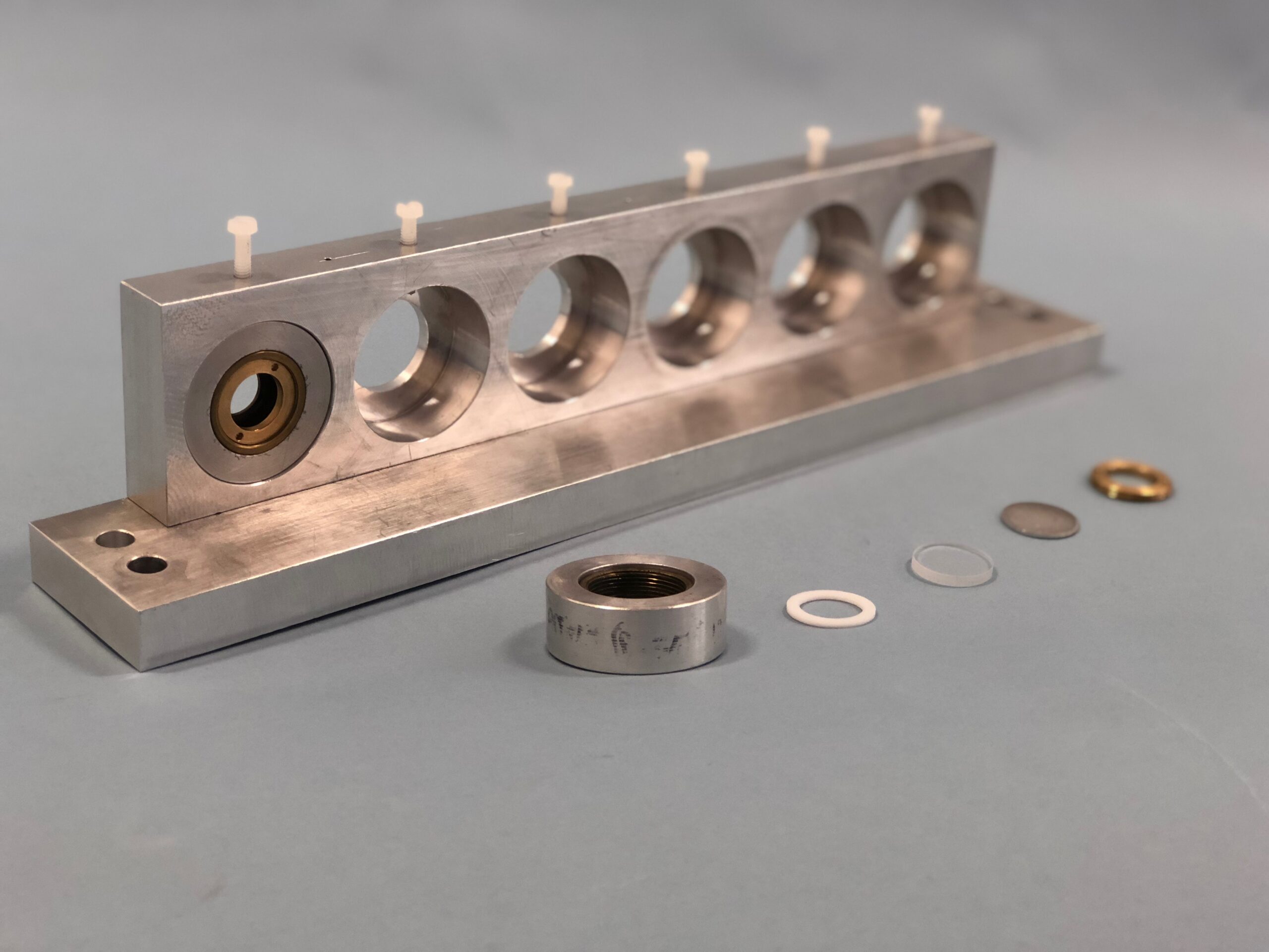 A metal rectangular sample holder, with circular holes in